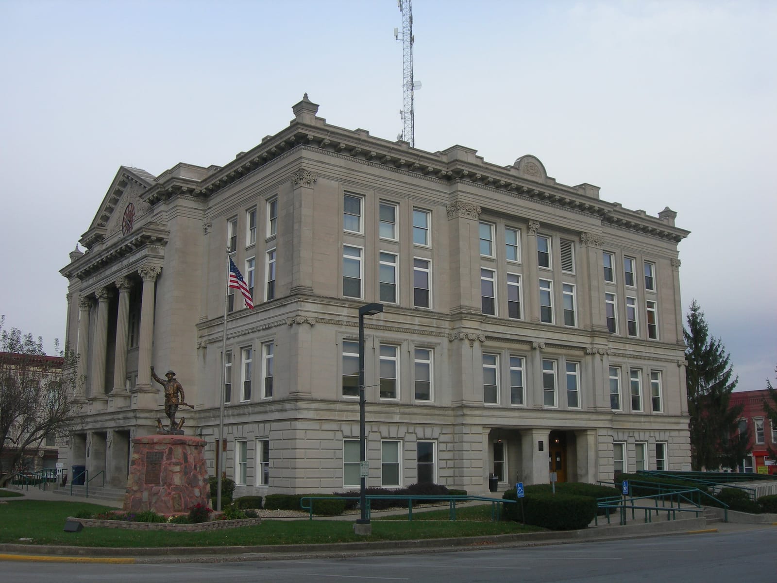The Putnam County Courthouse in Greencastle, Indiana, a classical stone building with columns, an American flag, and the Doughboy statue in front.