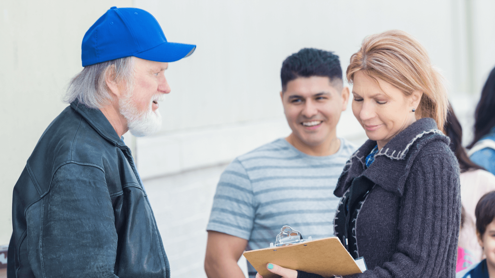 Three campaign volunteers having a warm conversation outside while holding a clipboard.